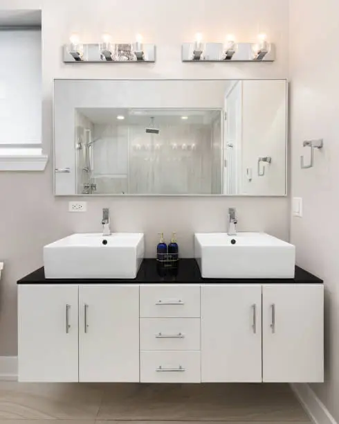 Contemporary vanity setup with dual sinks, under-sink cabinets, and mirror lighting.