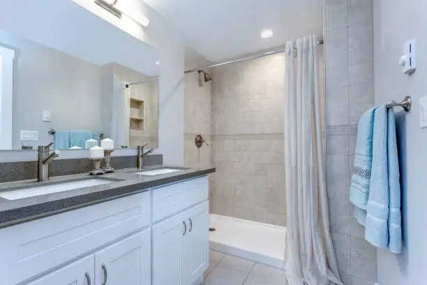 Sleek walk-in shower and double vanity with updated tile in a bright bathroom.