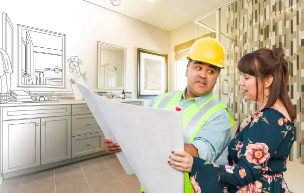 Contractor and homeowner reviewing blueprints in a bathroom under renovation.