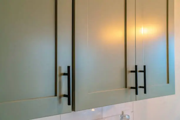 Freshly painted kitchen cabinets with updated brass hardware for a cost-effective upgrade.