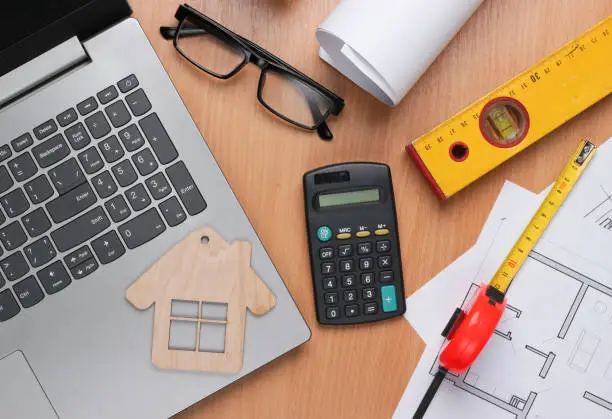 A budgeting spreadsheet open on a laptop next to renovation materials and a calculator.