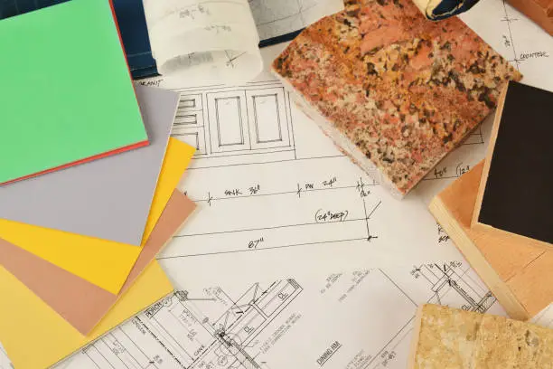 Detailed kitchen and bathroom remodel estimates spread out on a table next to wellness design sketches