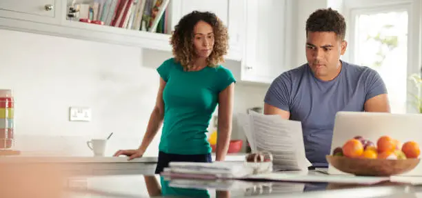 Couple reviewing remodeling budget documents in a bright kitchen, with focus on long-term health and efficiency upgrades.