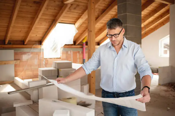 Architect reviewing attic remodel costs and returns – attic home remodeling budgeting