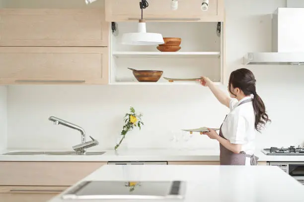 A person cleaning or organizing open kitchen shelves.