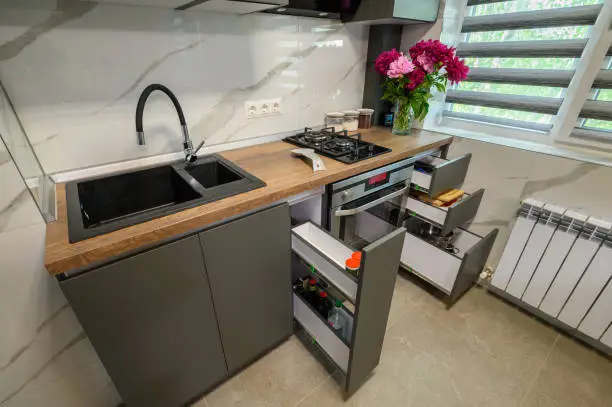 A small kitchen with innovative storage solutions like pull-out cabinets, under-sink drawers, and vertical pantry shelves.