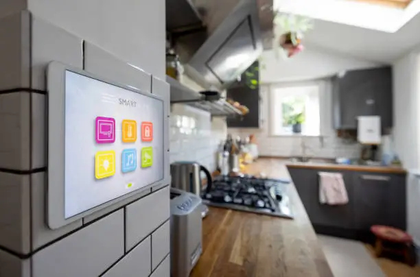 Smart home control panel in a kitchen, used to manage voice-activated appliances and audio systems.