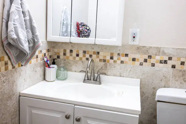 Affordable small bathroom renovation using peel-and-stick tiles and repainted cabinetry.