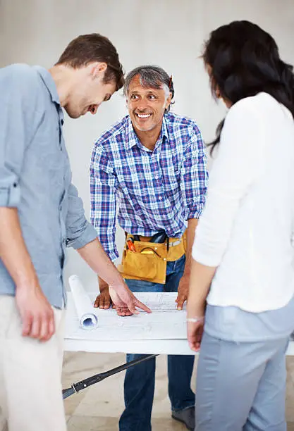 Remodel contractor showing design plans to clients for custom hidden storage solutions
