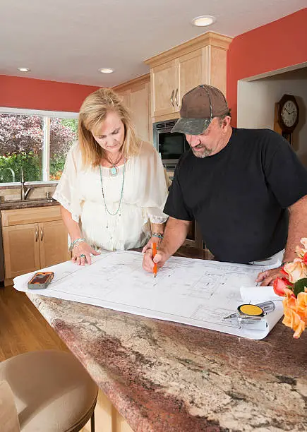 Kitchen remodeling contractor reviewing a budget remodel blueprint with a homeowner.