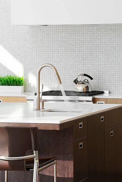 A sleek kitchen faucet with aerator running in a modern kitchen with clean surfaces.