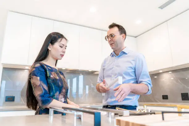 contractor discussing a 3D high-altitude kitchen design with a client in a showroom.