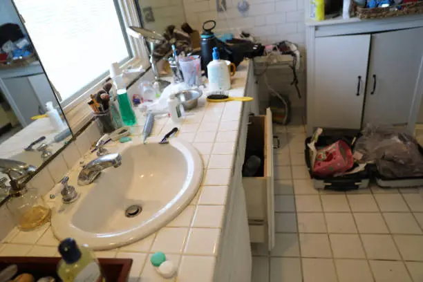 Bathroom with poor lighting and cluttered storage.