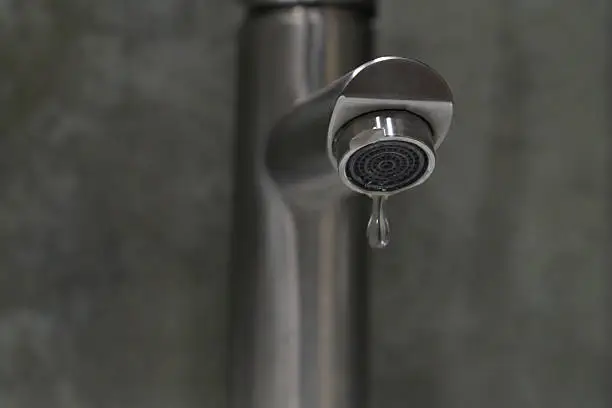  Leaky bathroom faucet being repaired, highlighting maintenance costs.