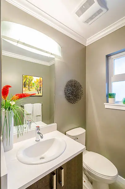 Small bathroom with large mirror and light color palette, enhancing space.