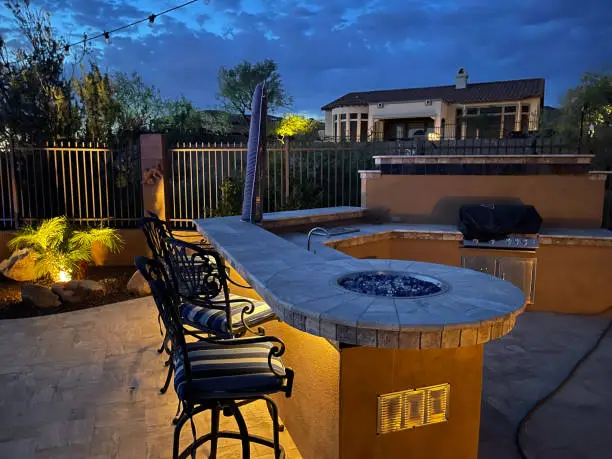 outdoor kitchen with lighting, fire pit, and added features